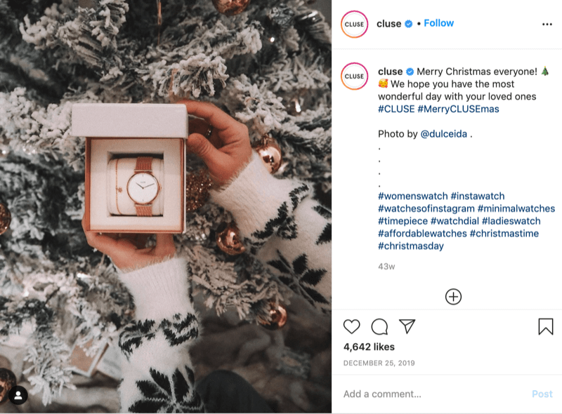 Publicación de Instagram de @cluse que muestra una foto de una modelo con suéter de copo de nieve sosteniendo un reloj frente a un árbol nevado por @dulceida con los hashtags #cluse y #meryclusemas